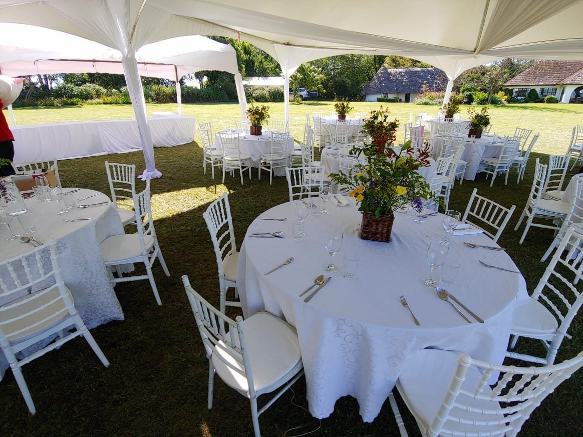 Outdoor reception with white chairs and floral table settings