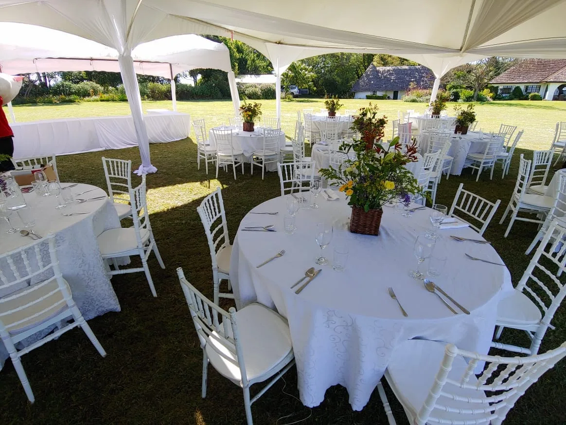 Outdoor reception with white chairs and floral table settings