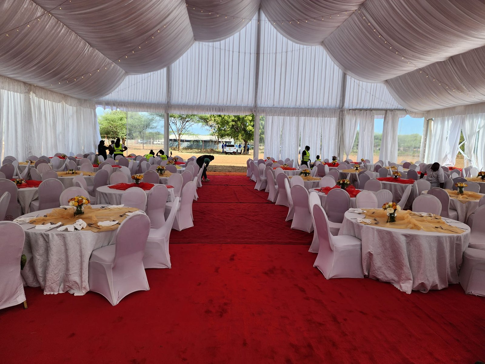 Draped marquee with banquet tables and a central red carpet