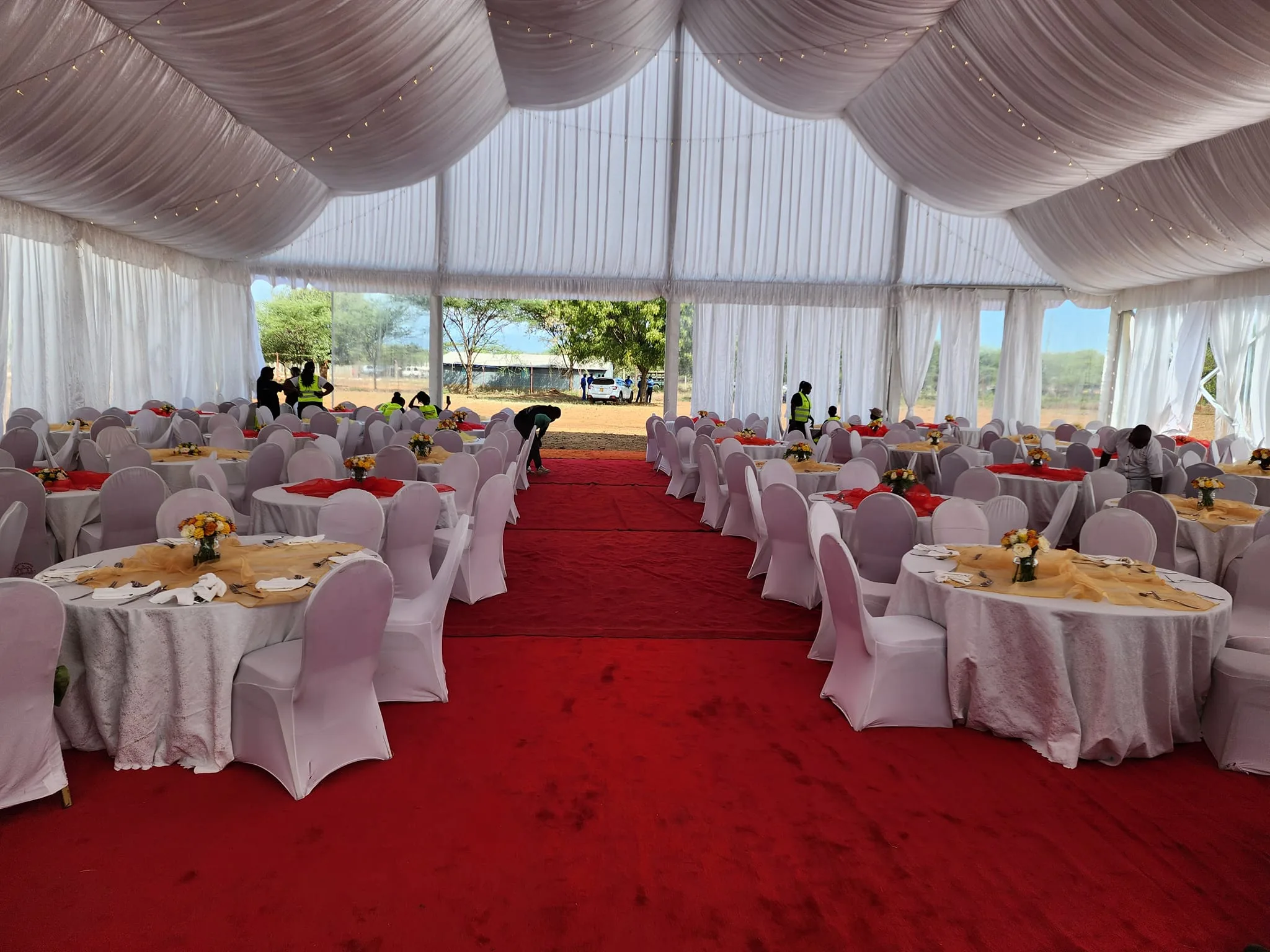 Draped marquee with banquet tables and a central red carpet